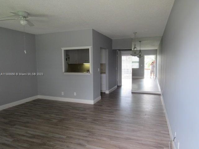 spare room featuring dark hardwood / wood-style floors, a textured ceiling, and ceiling fan with notable chandelier