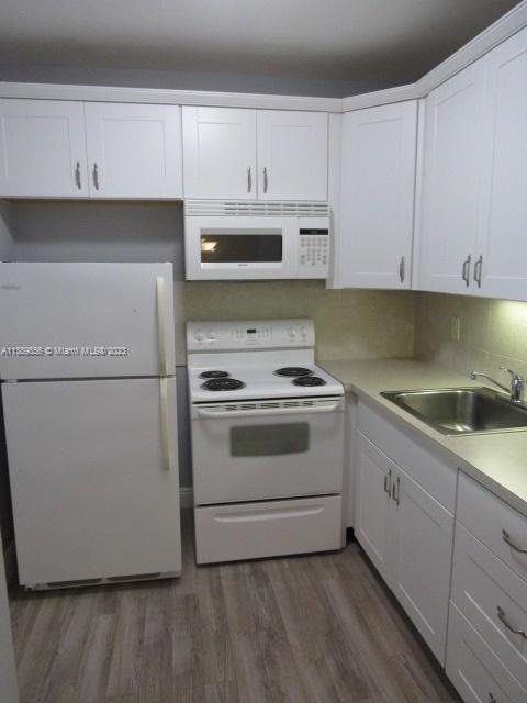 kitchen with white appliances, white cabinets, dark wood-type flooring, and sink