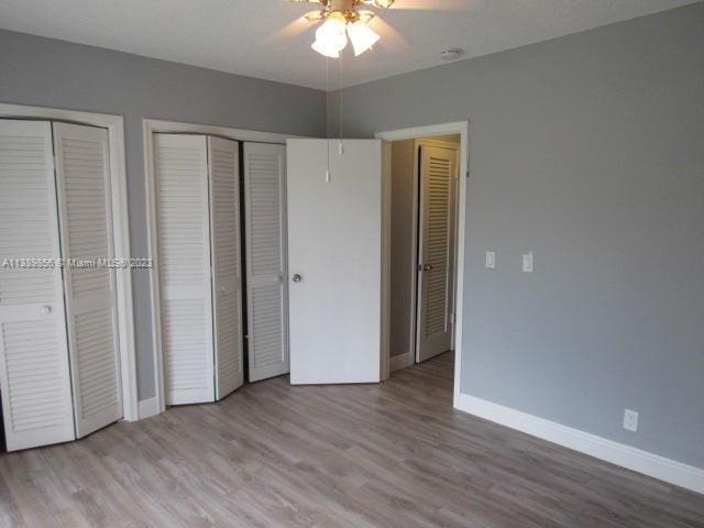 unfurnished bedroom with two closets, ceiling fan, and light hardwood / wood-style flooring