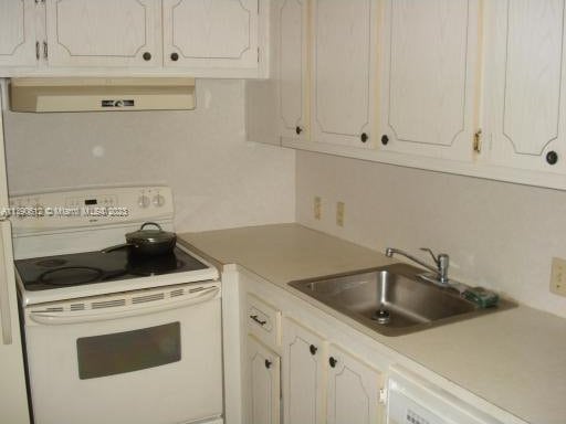 kitchen with white appliances, white cabinetry, exhaust hood, and sink