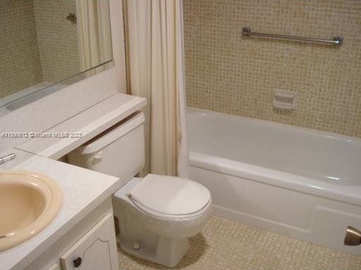 full bathroom featuring shower / bath combination with curtain, tile floors, vanity with extensive cabinet space, and toilet