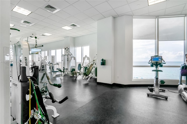 exercise room featuring a water view and a drop ceiling