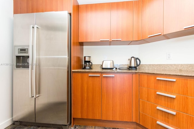 kitchen featuring light stone countertops and stainless steel refrigerator with ice dispenser