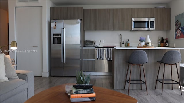 kitchen featuring a breakfast bar, light hardwood / wood-style flooring, sink, and stainless steel appliances