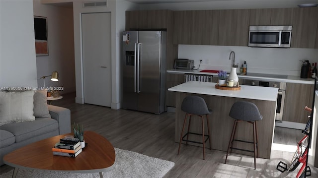 kitchen featuring a breakfast bar, light hardwood / wood-style floors, sink, stainless steel appliances, and a center island