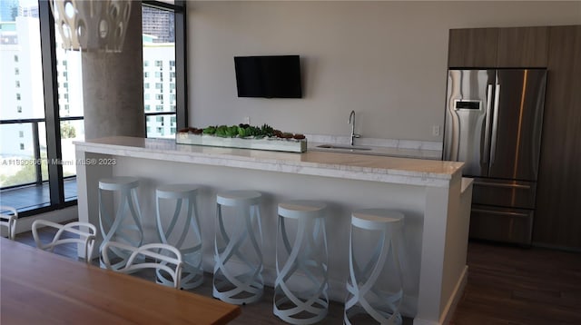 interior space with stainless steel fridge, sink, a breakfast bar, and a wealth of natural light