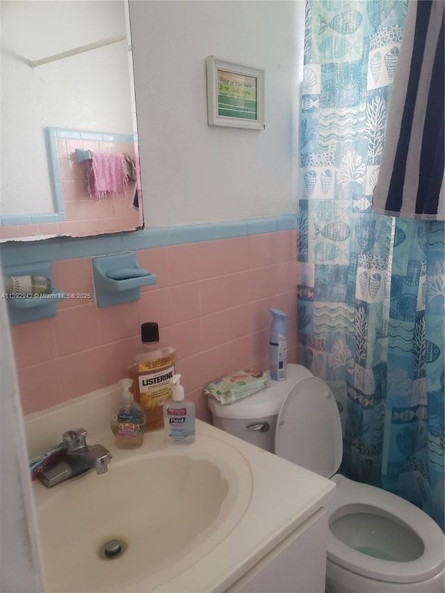 bathroom featuring vanity, curtained shower, toilet, and tile walls