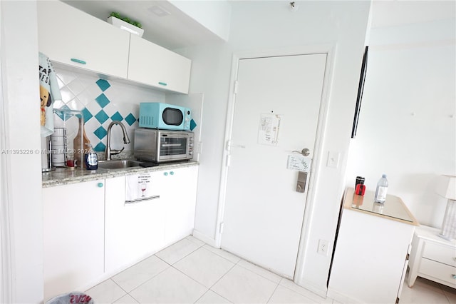 kitchen featuring backsplash, light tile floors, and white cabinetry