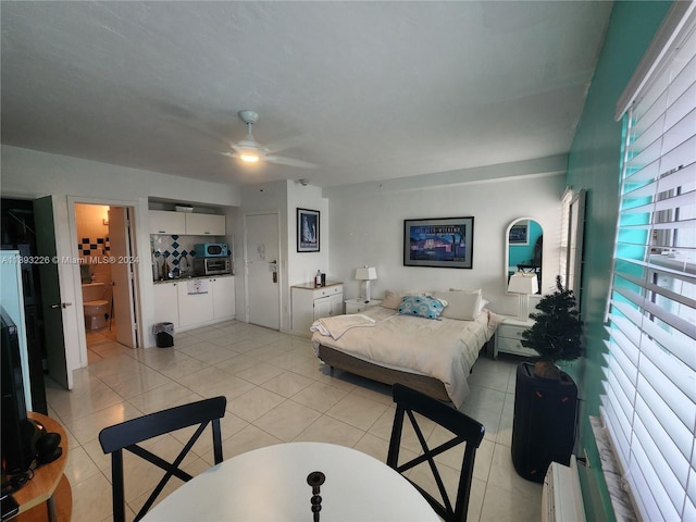 bedroom featuring light tile floors, ensuite bath, and ceiling fan