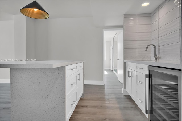 kitchen with beverage cooler, backsplash, a center island, sink, and hardwood / wood-style flooring