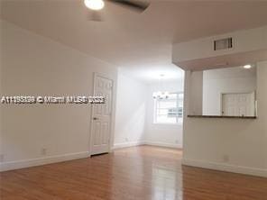 spare room featuring ceiling fan with notable chandelier and wood-type flooring