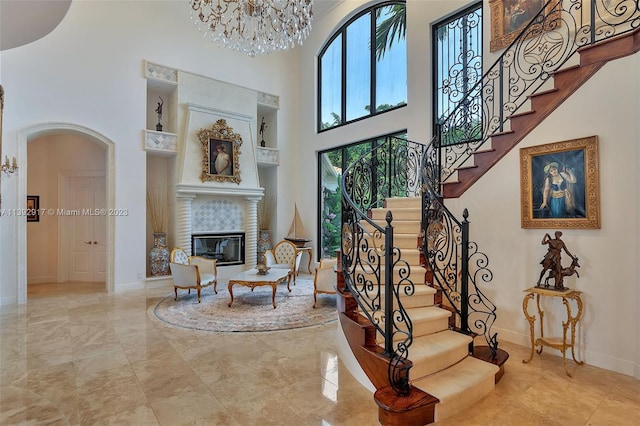 stairway featuring light tile floors, a fireplace, a chandelier, and a towering ceiling