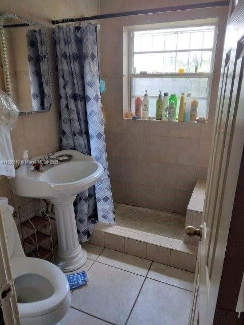 bathroom featuring curtained shower, tile flooring, plenty of natural light, and toilet