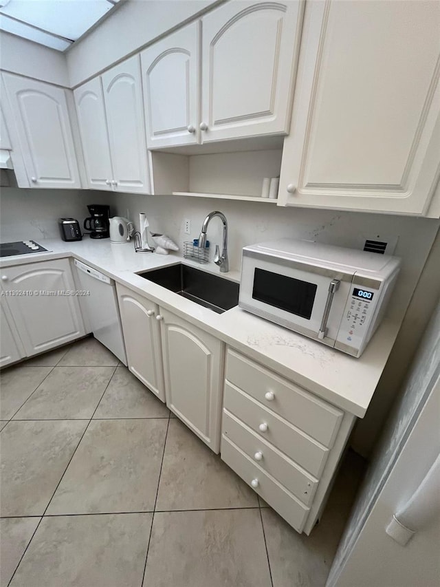 kitchen with light tile floors, white cabinets, white appliances, and sink