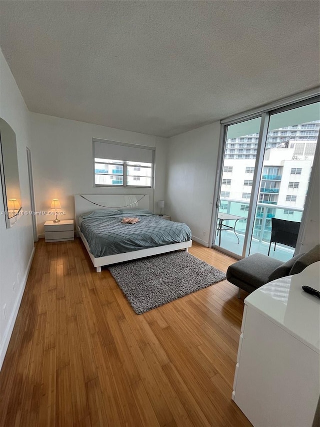 bedroom featuring a textured ceiling, hardwood / wood-style floors, and access to exterior