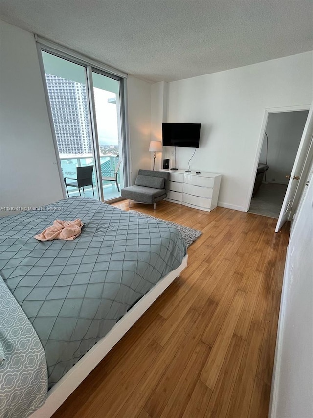 bedroom featuring a textured ceiling, light hardwood / wood-style floors, and access to exterior