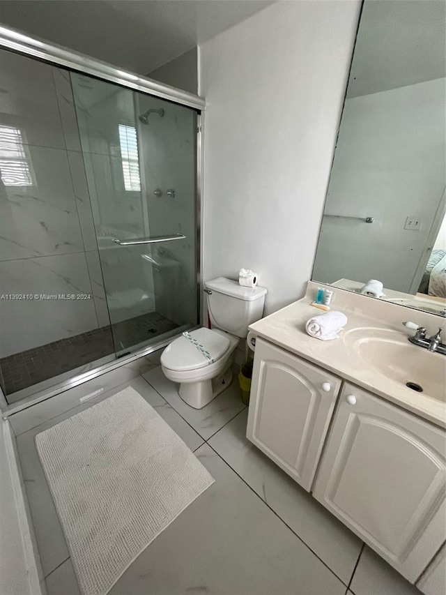 bathroom with a shower with door, tile floors, vanity, and toilet