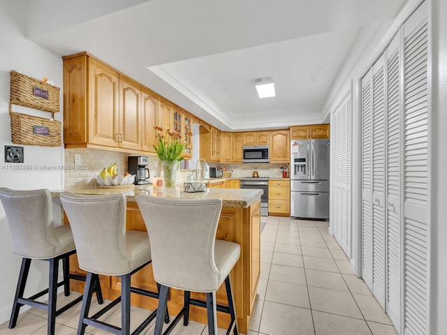 kitchen featuring backsplash, appliances with stainless steel finishes, and a breakfast bar area