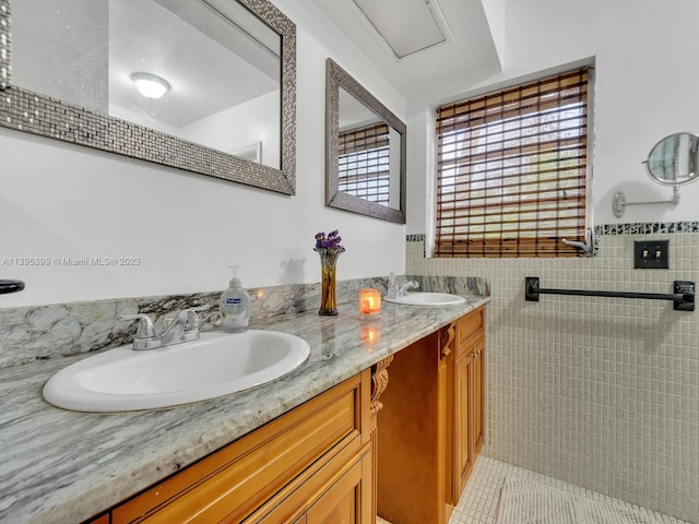 bathroom with double sink, a healthy amount of sunlight, tile walls, and large vanity