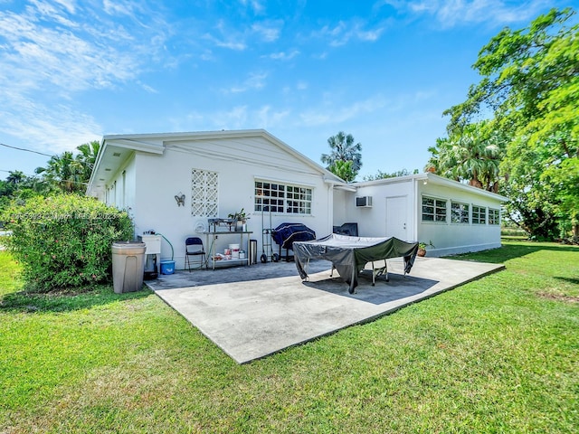 rear view of property featuring a patio area, a wall mounted air conditioner, and a lawn