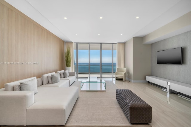 living room with a water view, wooden walls, and expansive windows