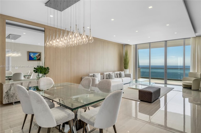 dining area featuring an inviting chandelier, expansive windows, light tile floors, and a water view