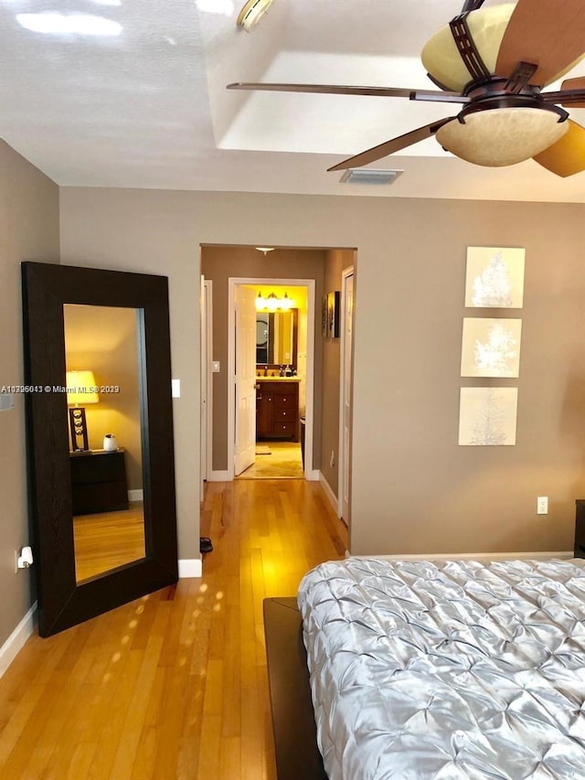 bedroom featuring connected bathroom, ceiling fan, and light wood-type flooring