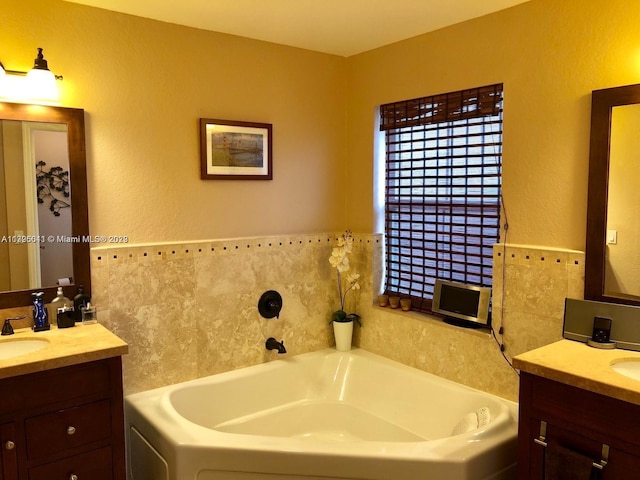 bathroom with a washtub and dual vanity