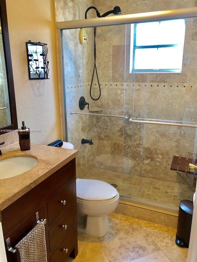 bathroom with an enclosed shower, vanity, tile floors, and toilet