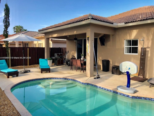 view of swimming pool featuring a grill, ceiling fan, and a patio area