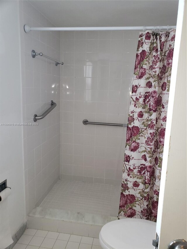 bathroom with toilet, tile flooring, and tiled shower