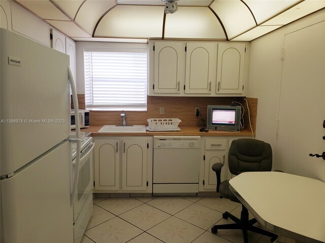 kitchen with white appliances, backsplash, sink, and light tile floors