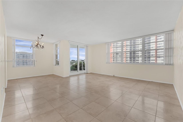 unfurnished room with baseboards, tile patterned flooring, and an inviting chandelier