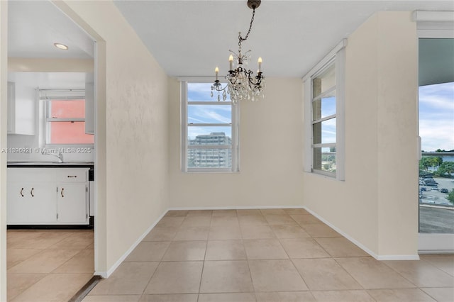 unfurnished dining area with baseboards, a chandelier, a sink, and light tile patterned flooring