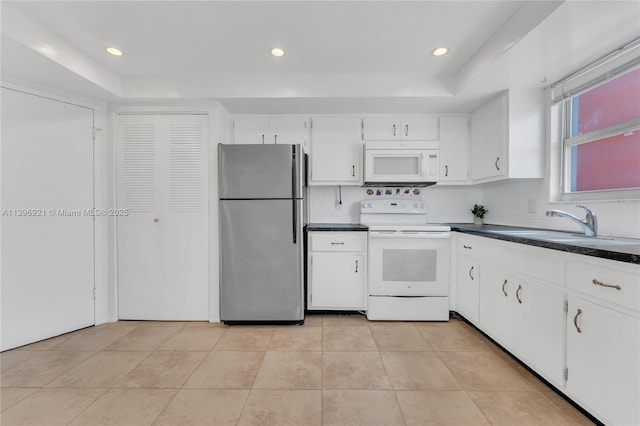 kitchen with white appliances, a sink, white cabinets, decorative backsplash, and dark countertops