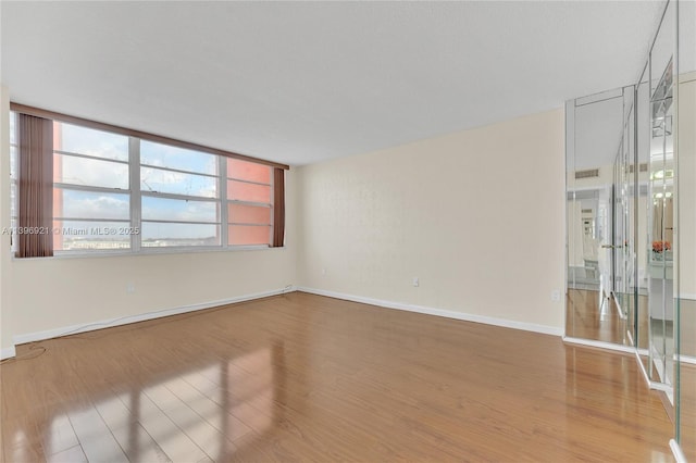 spare room featuring baseboards and wood finished floors