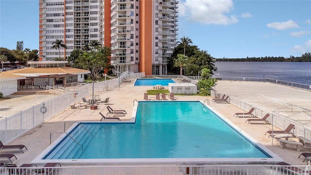 pool with a water view, a patio area, and fence