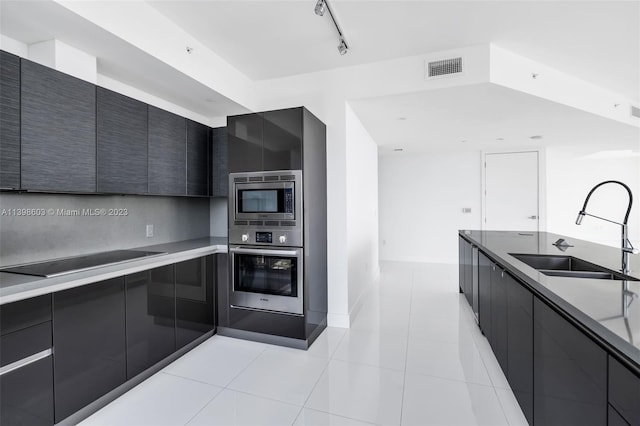 kitchen featuring stainless steel appliances, sink, light tile floors, and track lighting