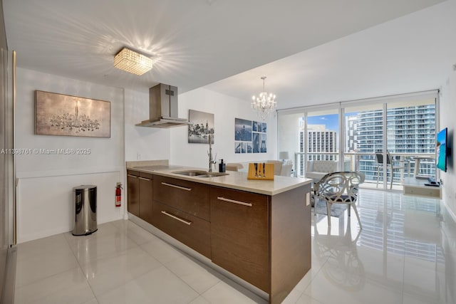 kitchen featuring extractor fan, sink, dark brown cabinetry, expansive windows, and light tile patterned floors