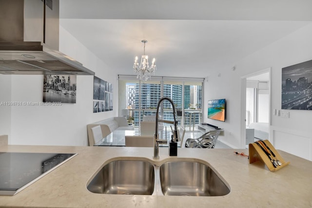 kitchen featuring sink, hanging light fixtures, island range hood, a notable chandelier, and black stovetop