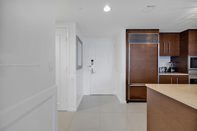 kitchen with paneled built in refrigerator, light tile patterned floors, and stainless steel oven