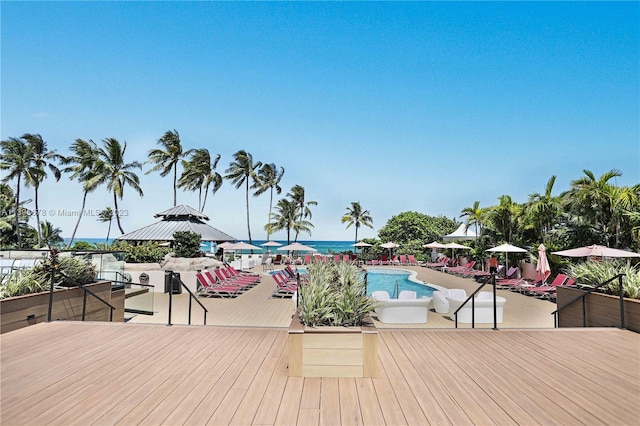 wooden deck featuring a gazebo, a community pool, and a water view