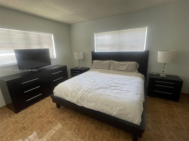 bedroom with a textured ceiling and tile floors