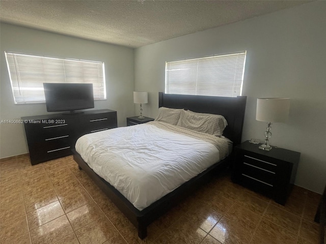 bedroom with a textured ceiling and tile floors