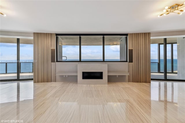 unfurnished living room featuring a water view, floor to ceiling windows, and light tile floors