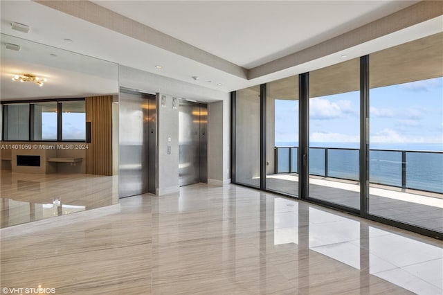 tiled spare room featuring elevator, expansive windows, and a water view