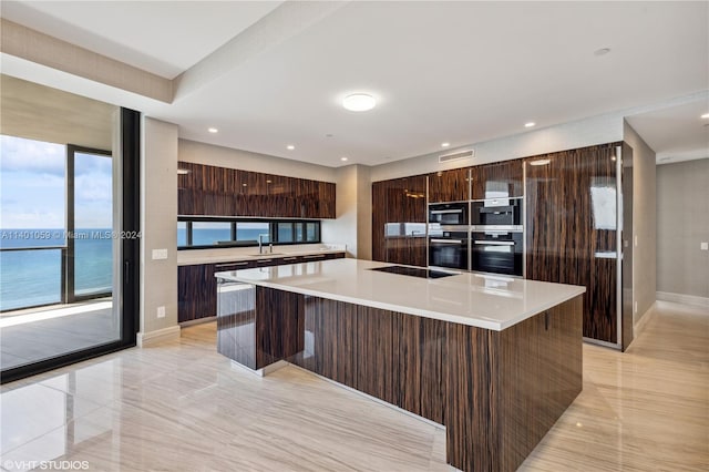 kitchen featuring light tile floors, a kitchen island, dark brown cabinetry, and sink