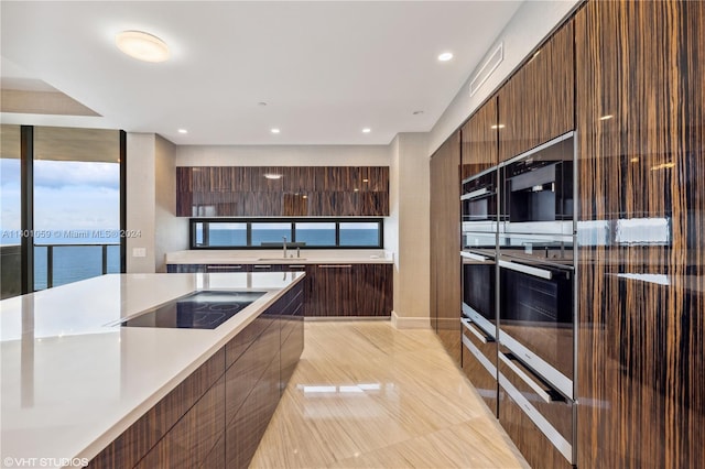 kitchen with stainless steel double oven, a water view, black electric stovetop, and sink