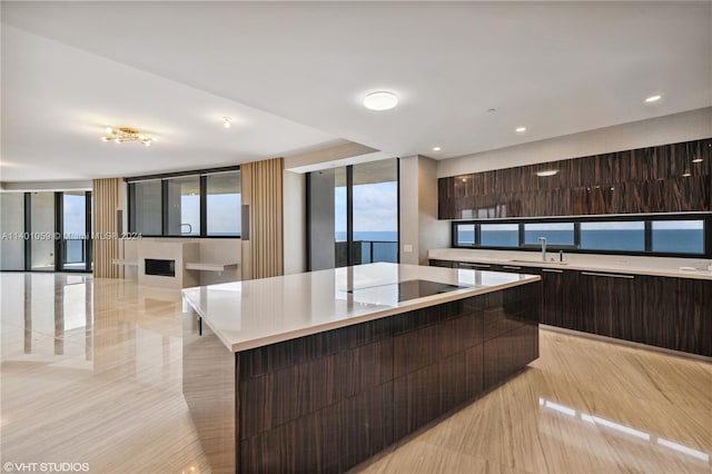 kitchen featuring a center island, black electric stovetop, dark brown cabinetry, and sink