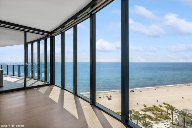 unfurnished sunroom with a water view and a view of the beach